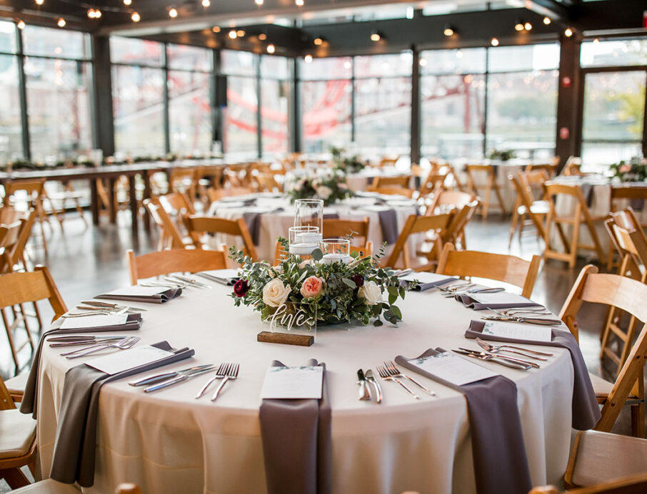 Romantic natural wedding table setup with ivory linens, brown satin napkins, and a greenery centerpiece at The Bridge Building, a downtown Nashville wedding venue