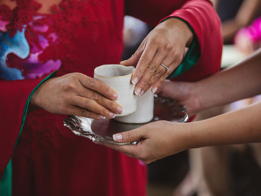 A close-up of a bride lifting tea off a sterling silver tray for her traditional Vietnamese Tea Ceremony for a Vietnamese-American wedding at the Bridge Building, a downtown Nashville wedding venue