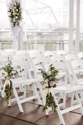 White Ceremony Setup on Rooftop with Floral Arrangements on Aisle Seats