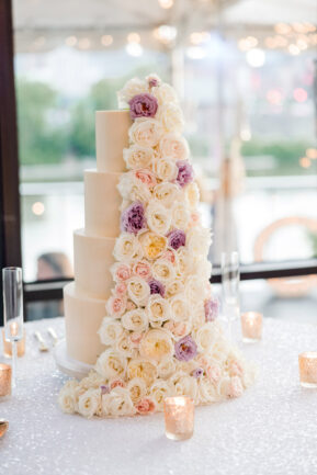 Four tier wedding cake with ivory and purple florals up one side