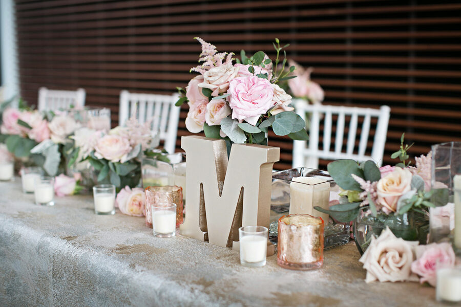 Glam pink wedding table decor with gold textured linens, abundant rose centerpiece arrangements, and votive candles at The Bridge Building, downtown Nashville wedding venue