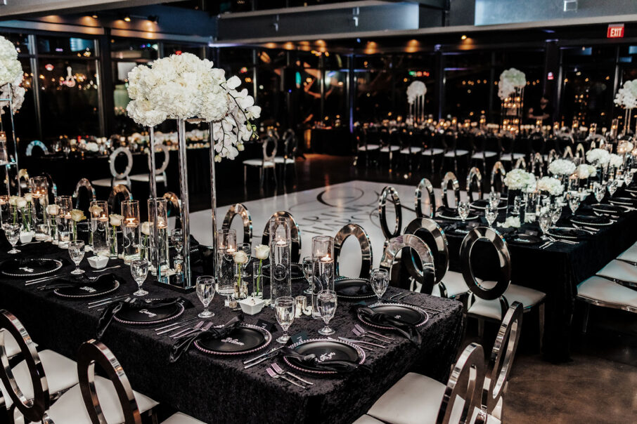 Glamorous wedding reception with silver chairs, black velvet table linens, elevated white hydrangea centerpieces, and floating candles at The Bridge Building, downtown Nashville wedding venue