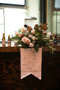 Wedding bar decor with love quote sign and wild arrangement with roses and magnolia leaves for romantic winter wedding at The Bridge Building, downtown Nashville wedding venue
