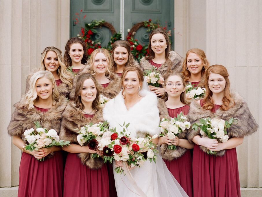 Bride in white fur shawl with maroon bridemaids in brown fur shawls for romantic winter wedding at The Bridge Building, downtown Nashville wedding venue