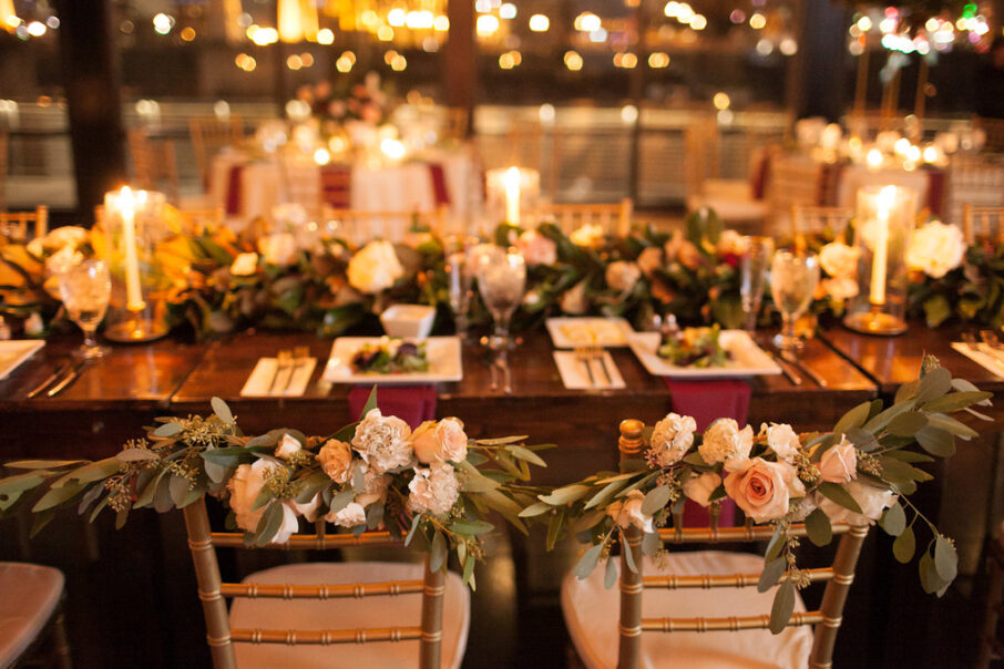 The bride and groom's chairs decorated with greenery and pink and ivory flower arrangements for romantic winter wedding at The Bridge Building, downtown Nashville wedding venue