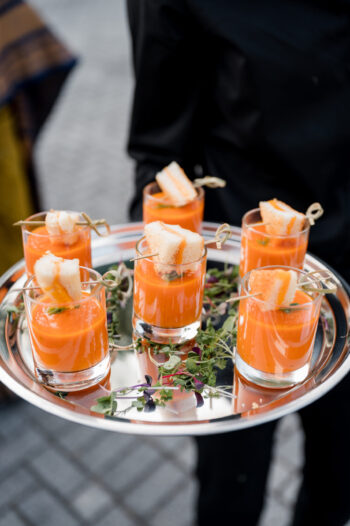Mini tomato soup shooters with small grilled cheeses on silver tray