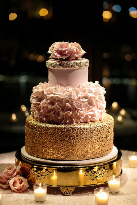 Unique wedding cake with different style tiers with gold beads, pink ruffle icing, and topped with baby pink roses for rose gold New Year's Eve wedding at the Bridge Building, a downtown Nashville wedding venue