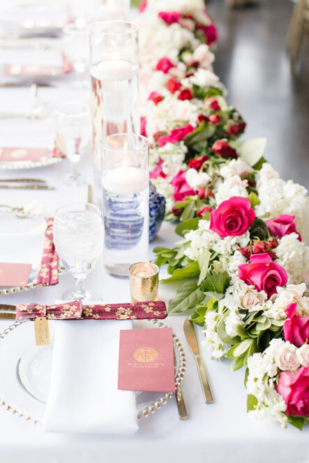 Close-up of wedding table setting with red rose and white hydrangea table runner and chopsticks for multicultural Chinese-American wedding at the Bridge Building, a downtown Nashville wedding venue