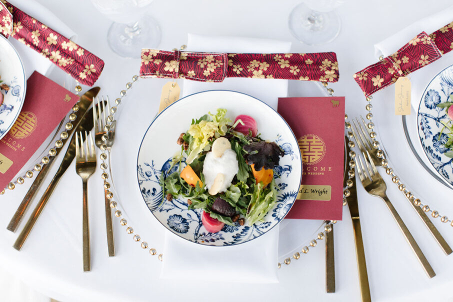 Place Setting with plated salad, custom chopsticks, wedding welcome card, and gold flatware