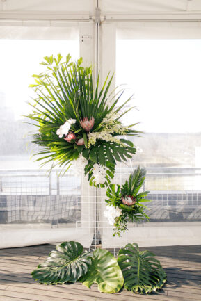 Ceremony altar arrangement with large tropical palm leaves and pink protea and white orchids for tropical-inspired wedding at the Bridge Building, a downtown Nashville wedding venue