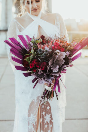 A bride in a celestial gown holding her Moody Purple Bridal Bouquet with Dried Florals