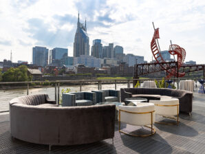 Modern lounge furniture on the riverfront patio overlooking the Cumberland River and downtown Nashville skyline