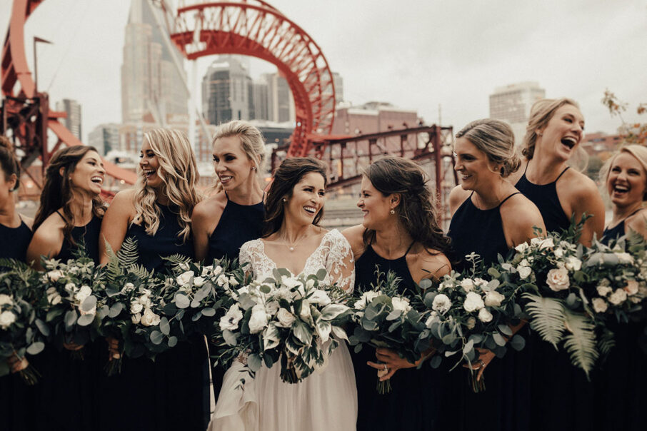 Bride laughs and poses with bridesmaids for candid wedding photo at the Bridge Building, a downtown Nashville wedding venue