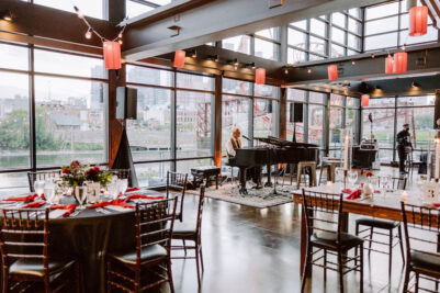 A pianist plays ahead of birthday party celebration at our private event venue decorated with red paper lanterns and tables set with red napkins and simple floral centerpieces